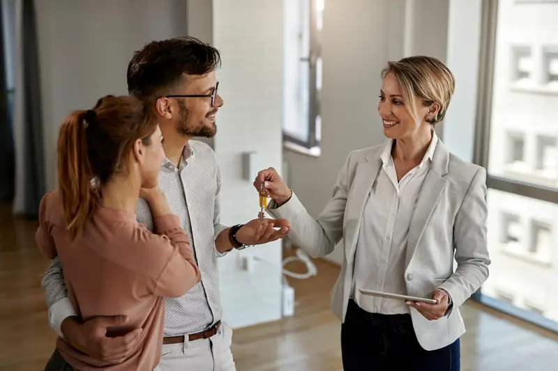 Agente immobilière remettant des clés à un couple