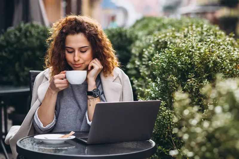 Femme remplissant un formulaire sur son ordinateur en terrasse